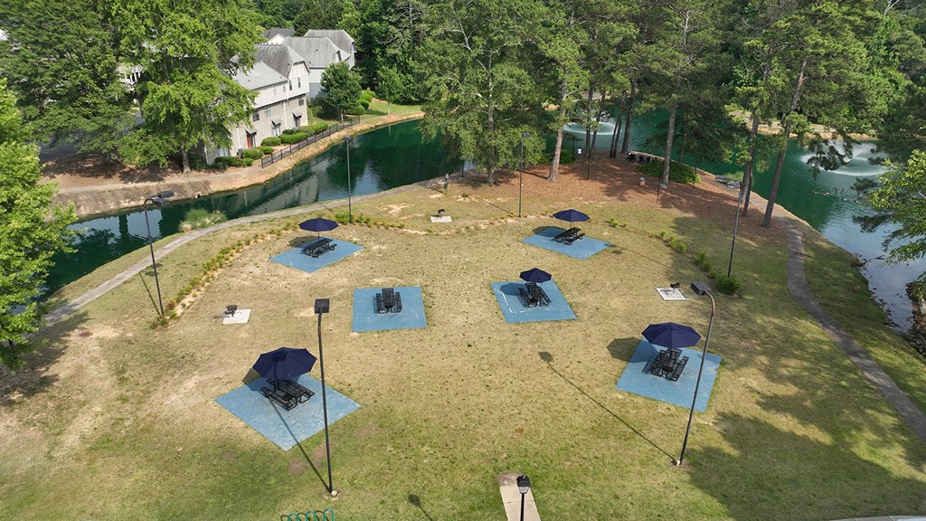 an aerial view of a campsite with blue mats and umbrellas on a grassy