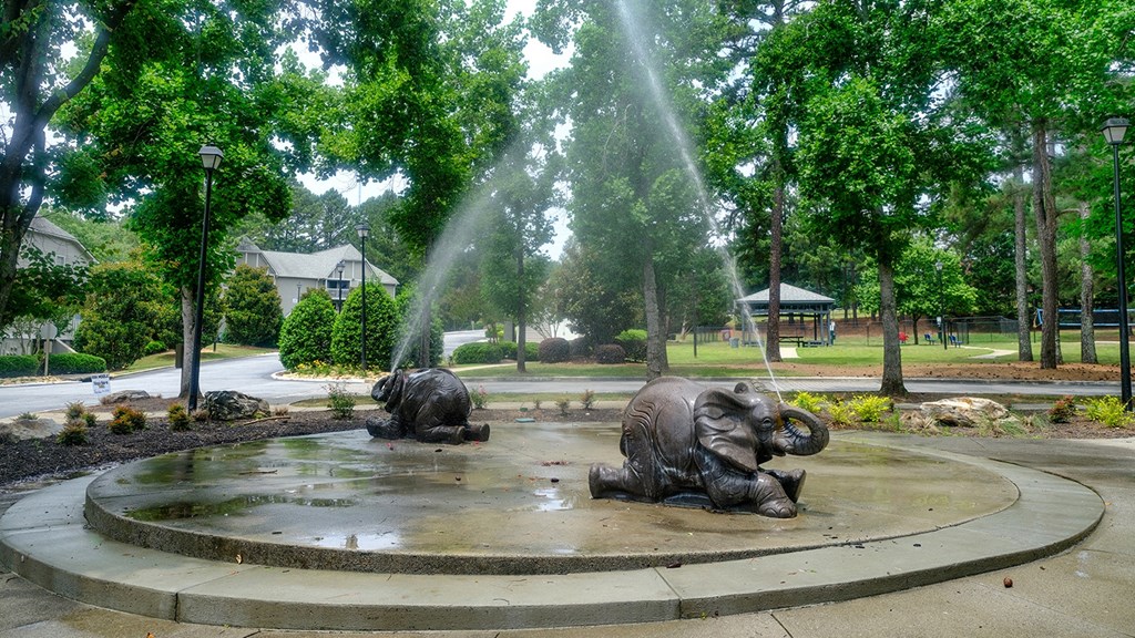 three elephants sit in a fountain in a park
