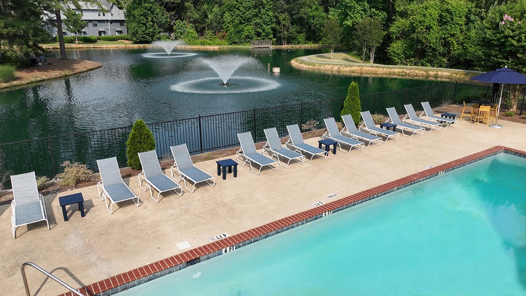 a swimming pool with chaise lounge chairs and a fountain in the background