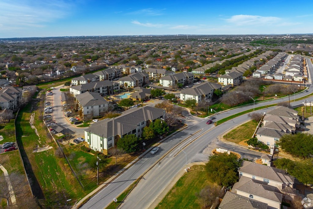A suburban area with apartment buildings and a road with cars.