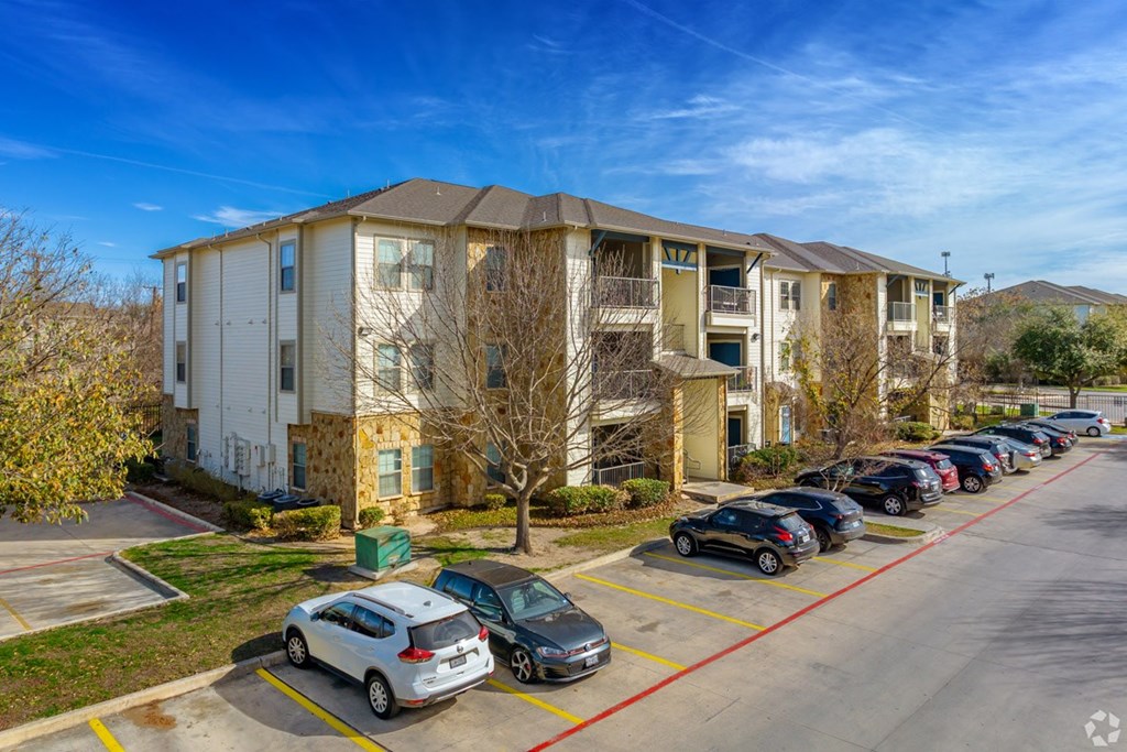 A parking lot with cars and apartment buildings in the background.