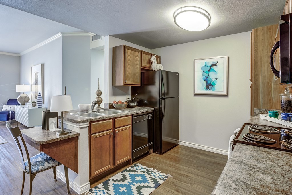 A kitchen with a black refrigerator and wooden cabinets.