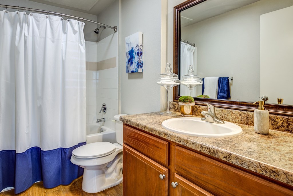 A bathroom with a white toilet, a brown counter, and a blue shower curtain.