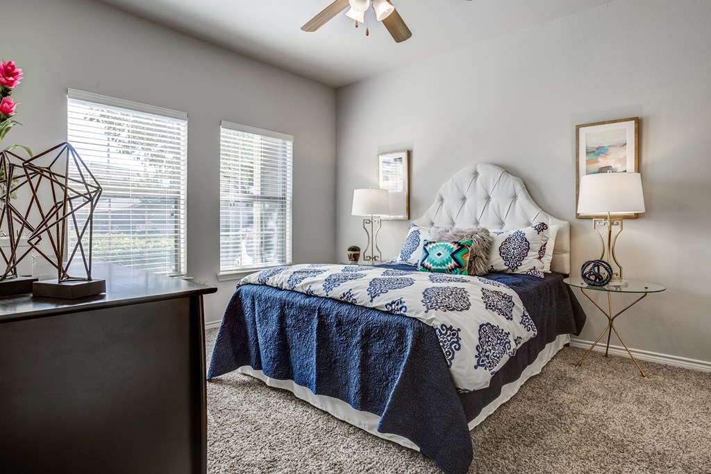 A bedroom with a bed, a dresser, and a ceiling fan.