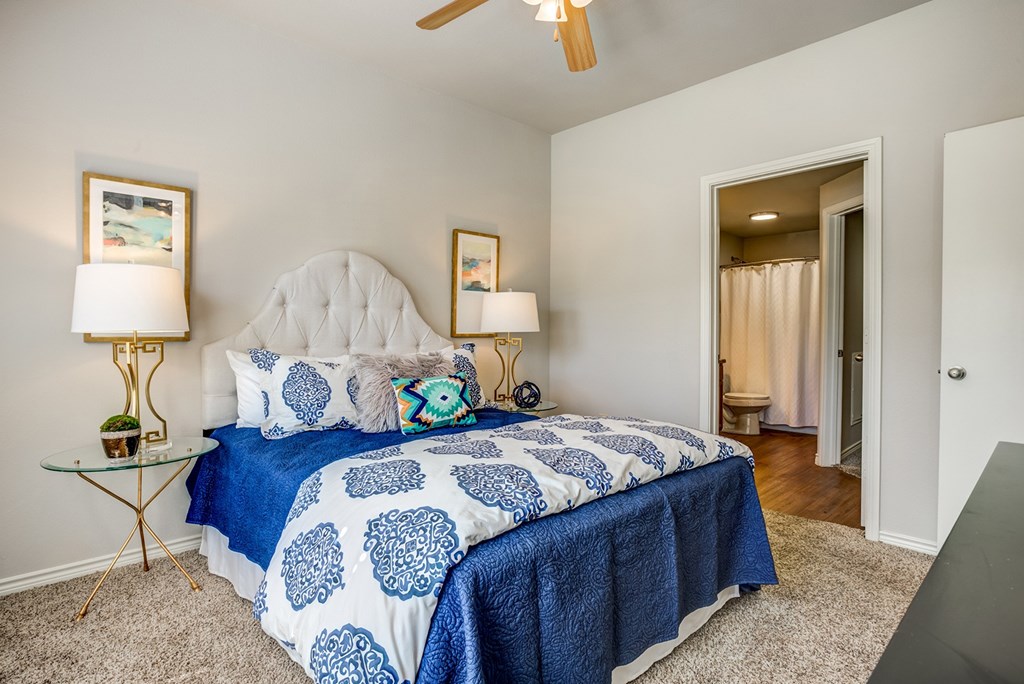 A bedroom with a bed covered in a blue and white patterned bedspread.