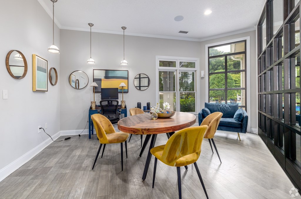 A modern dining room with a round table and yellow chairs.