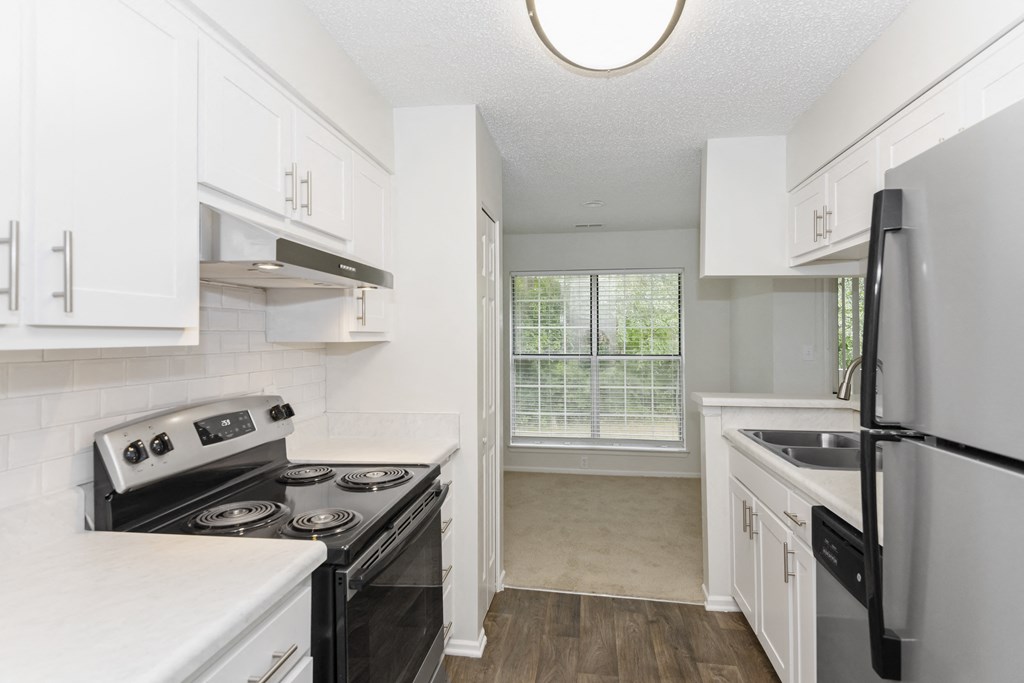 a kitchen with white cabinets and black stainless steel appliances at Canopy at Baybrook apartments in Charlotte NC