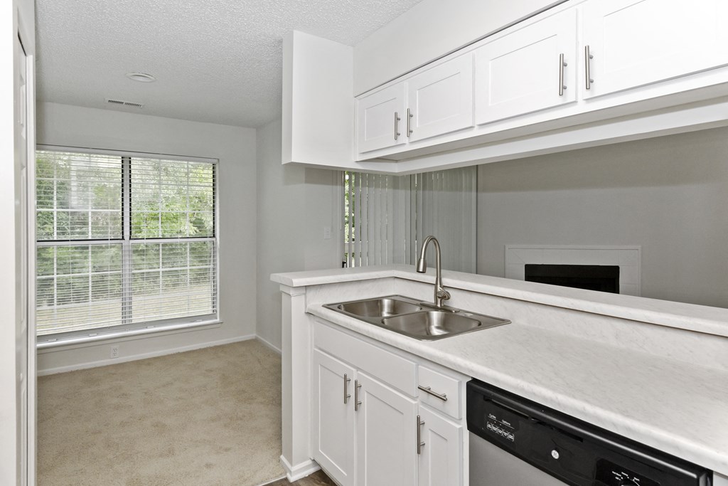 a kitchen with white cabinets and a large window at Canopy at Baybrook apartments in Charlotte NC