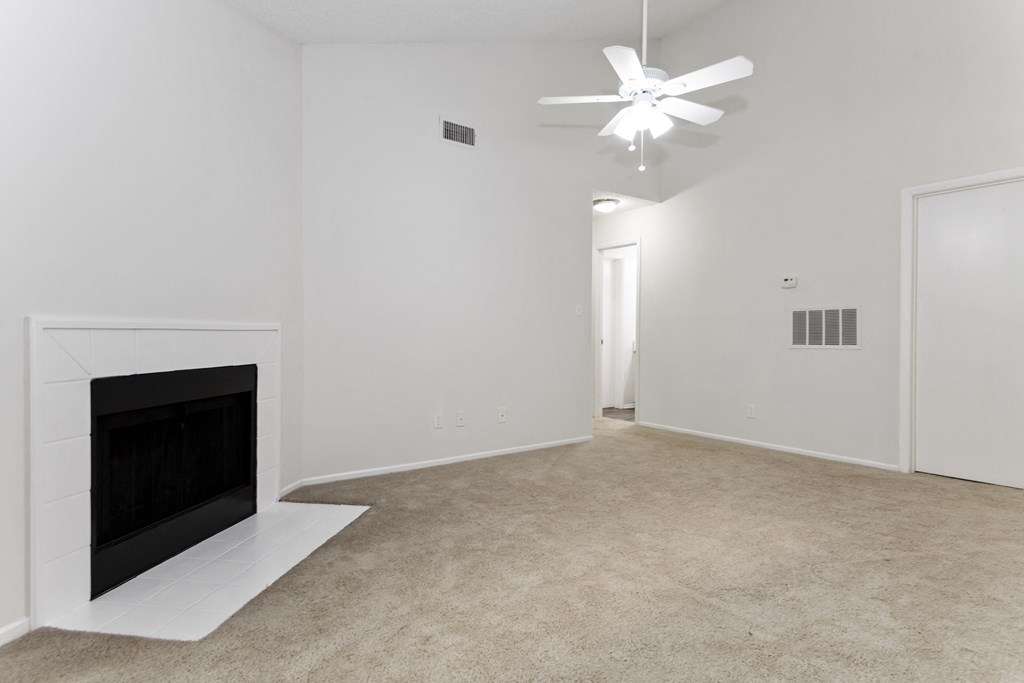 a living room with a fireplace and a vaulted ceiling and fan at Canopy at Baybrook apartments in Charlotte NC