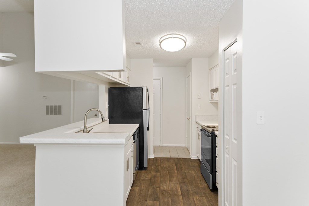 A black refrigerator is in a white kitchen.
