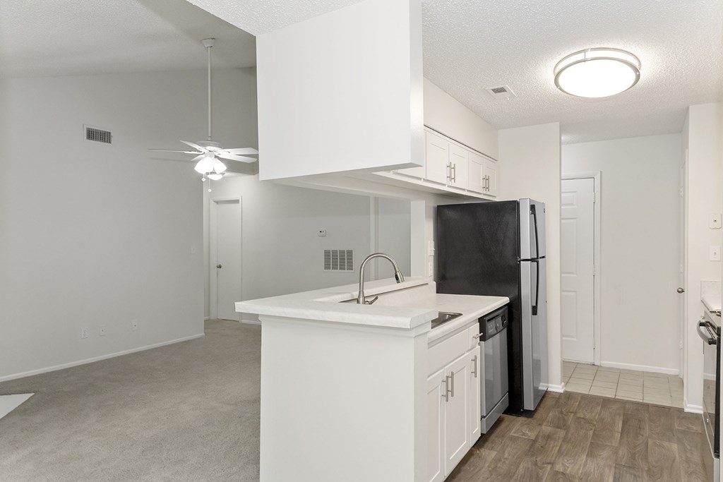 A kitchen with white cabinets and a black refrigerator.