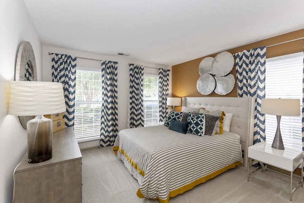 a bedroom with a large bed and a dresser with a lamp on it at Canopy apartments in South Charlotte