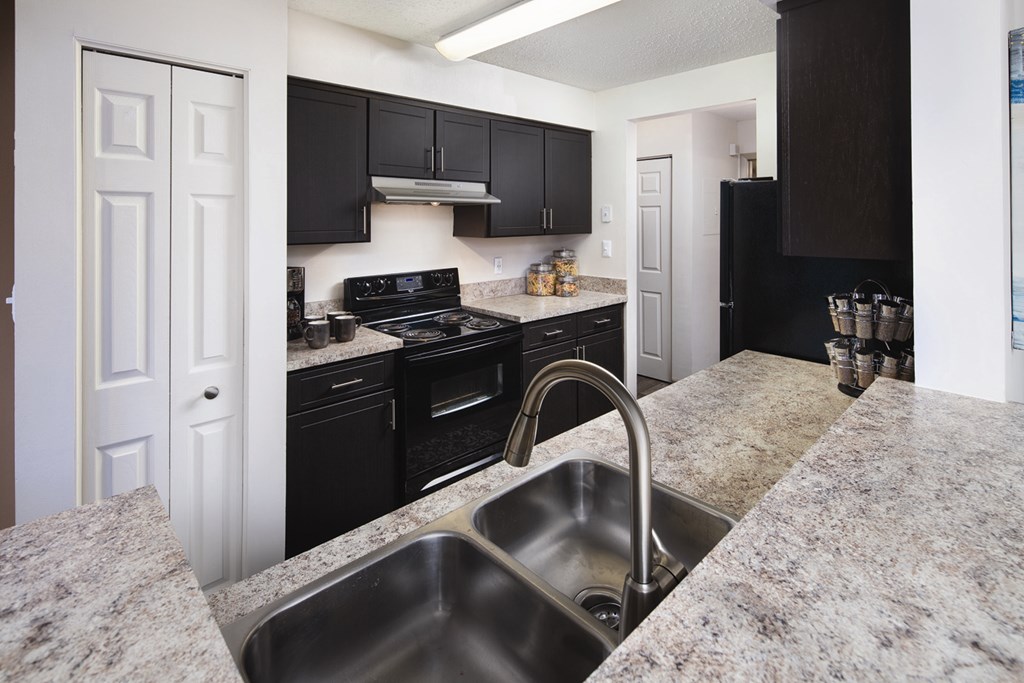 A kitchen with granite countertops and black cabinets.