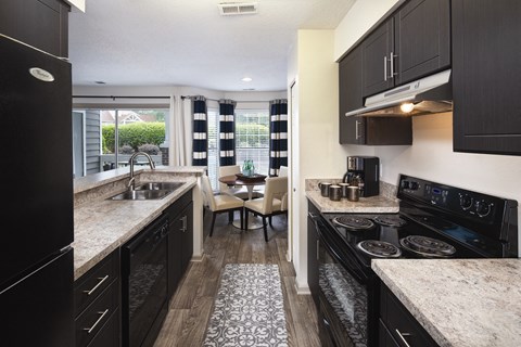 A kitchen with black cabinets and a granite countertop.