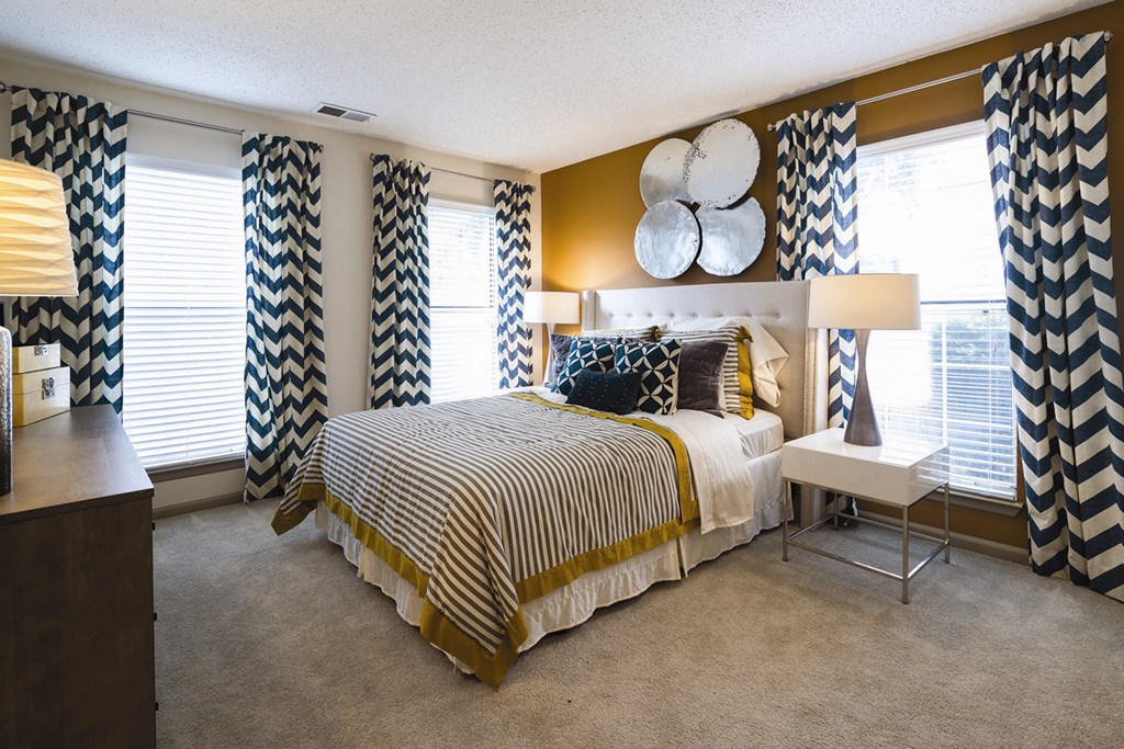 A bedroom with a large bed and a chair.