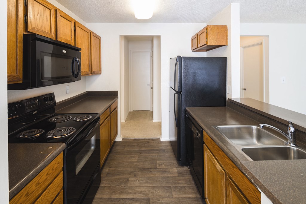 A kitchen with black appliances and wooden cabinets.
