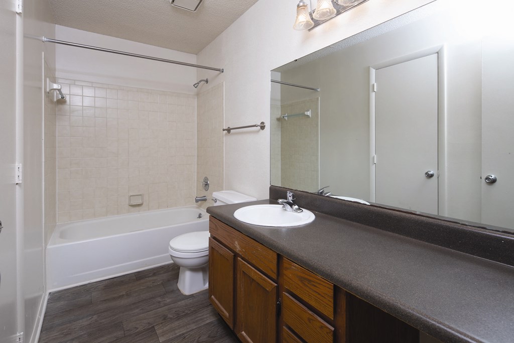 An empty bathroom with a white toilet, sink, and bathtub.