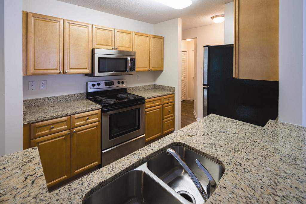 A kitchen with granite countertops and wooden cabinets.