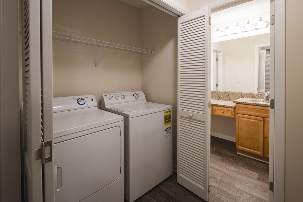 A hallway laundry room closet with white full size washer and dryer appliances