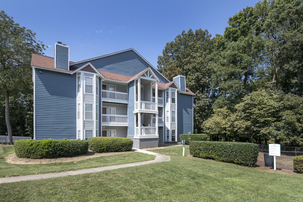 an apartment building with blue siding and a brown roof