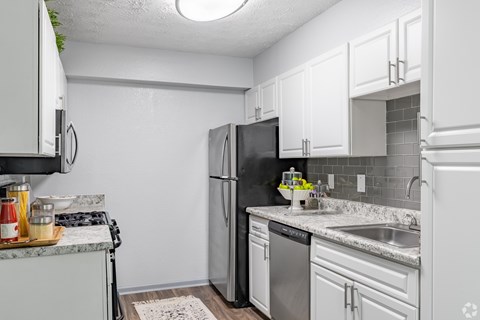 A kitchen with white cabinets and a black refrigerator.