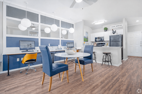 A modern kitchen and dining area with blue chairs and a white table.