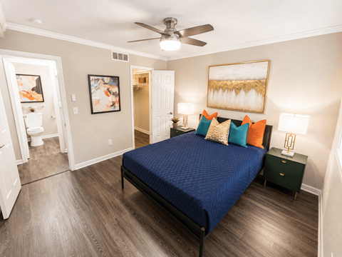 Pet-Friendly Garden-Style Apartments in Buckhead, GA - 55 Pharr - Bedroom With Blue Bedding, Colorful Pillows, Bedside Lamps, and Ceiling Fan.