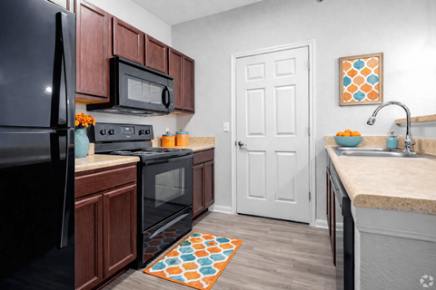 A kitchen with black appliances and wooden cabinets.
