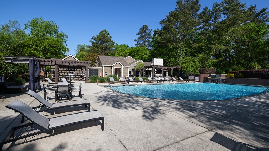 Wynnwood Vinings resident pool with lounge chairs and view of outdoor TV lounge with couches