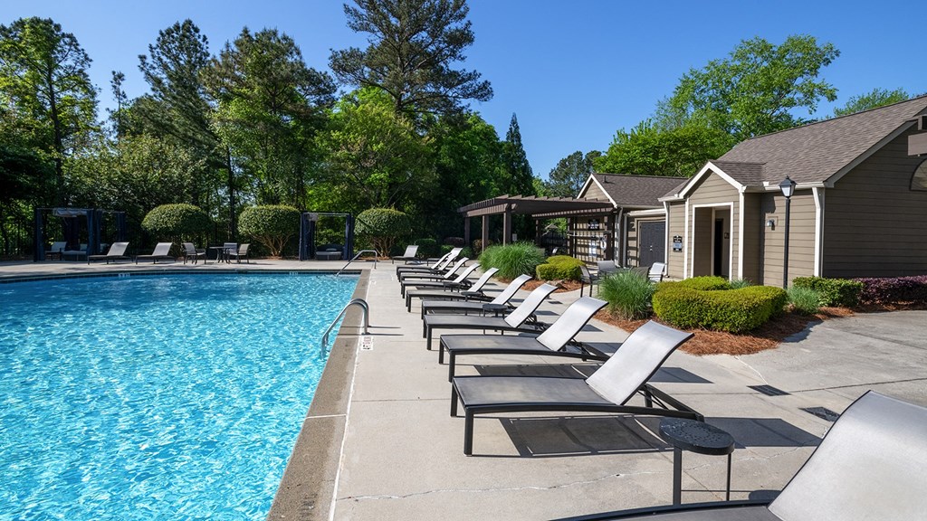 Wynnwood Vinings resident swimming pool with chaise lounge chairs and trees in the background