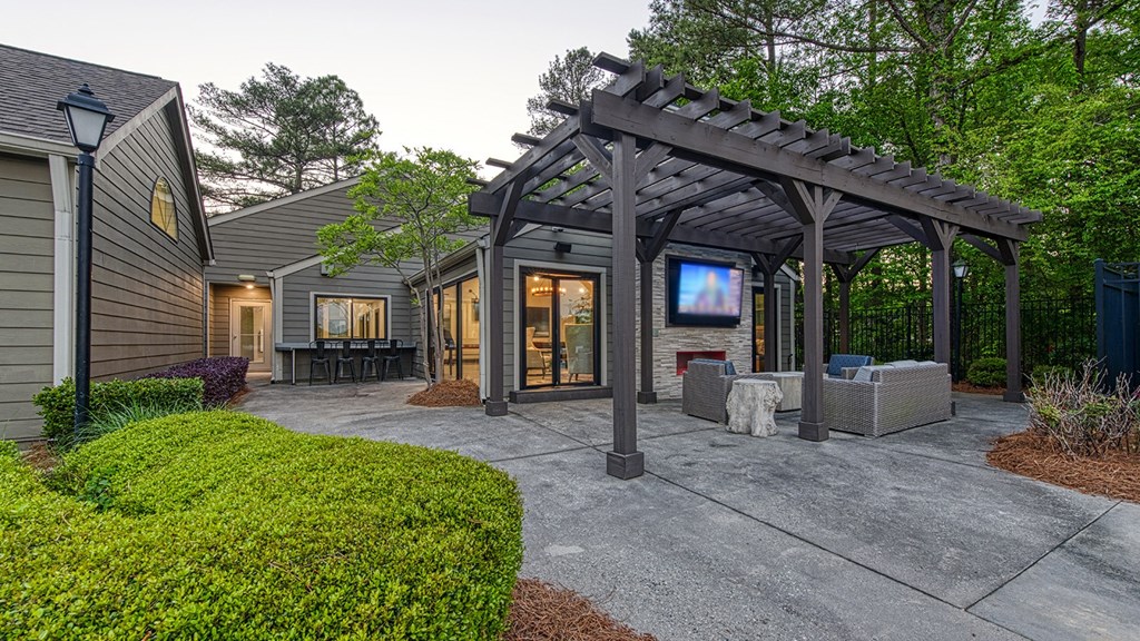 Wynnwood Vinings resident poolside lounge patio with glass entrance door and a pergola and TV with couches