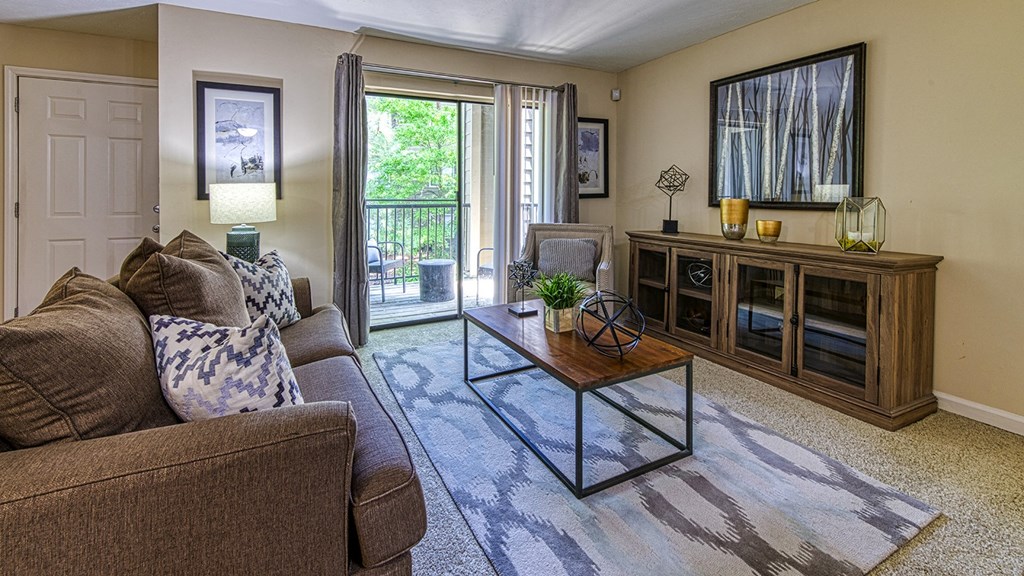 Apartments in Vinings, GA with In-Unit Washer and Dryer - Wynnwood Vinings - Furnished Living Room with Carpet Flooring and a Sliding Glass Door to a Private Balcony
