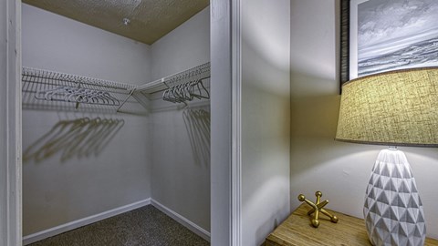 A lamp with a white shade and a gold base sits on a wooden table.