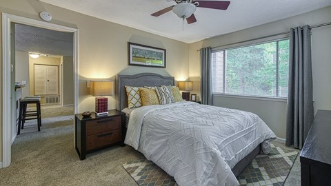 A bedroom with a bed, nightstand, and a ceiling fan.