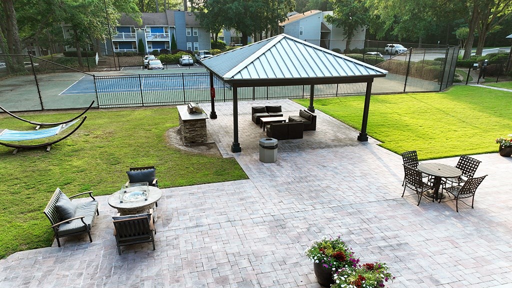 a large paver patio with a gazebo and a hammock next to a