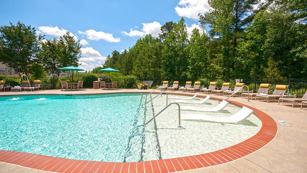 a swimming pool with chairs and umbrellas at Millennium Apartments Greenville SC