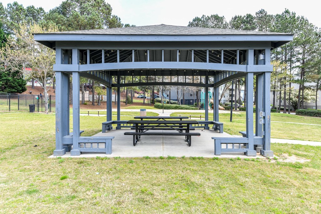 a pavilion with a picnic table and benches in a park