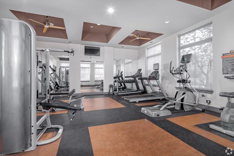 A spacious gym with a variety of equipment and a large mirror on the wall.