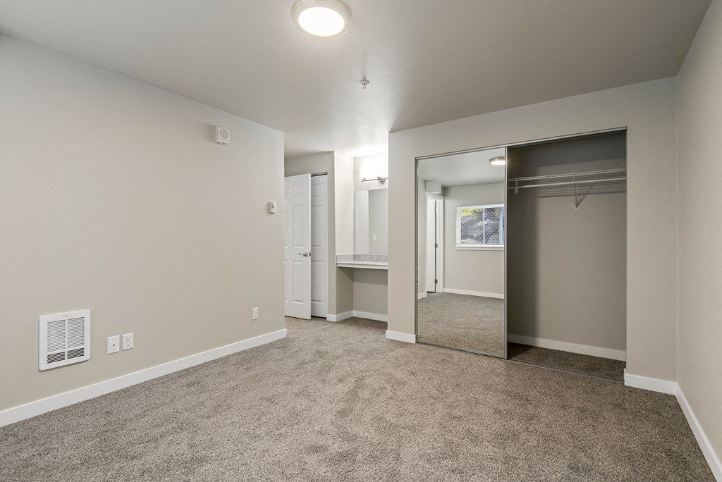 One-Bedroom Apartments in Tukwila, WA - Foster Creek - Unfurnished Bedroom with Carpet, Mirrored Closet, and Built-In Vanity with Mirror
