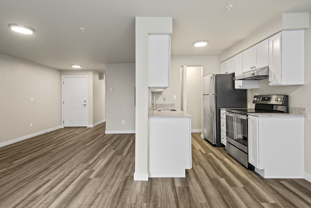 an empty kitchen with white cabinets and a stainless steel stove and refrigerator