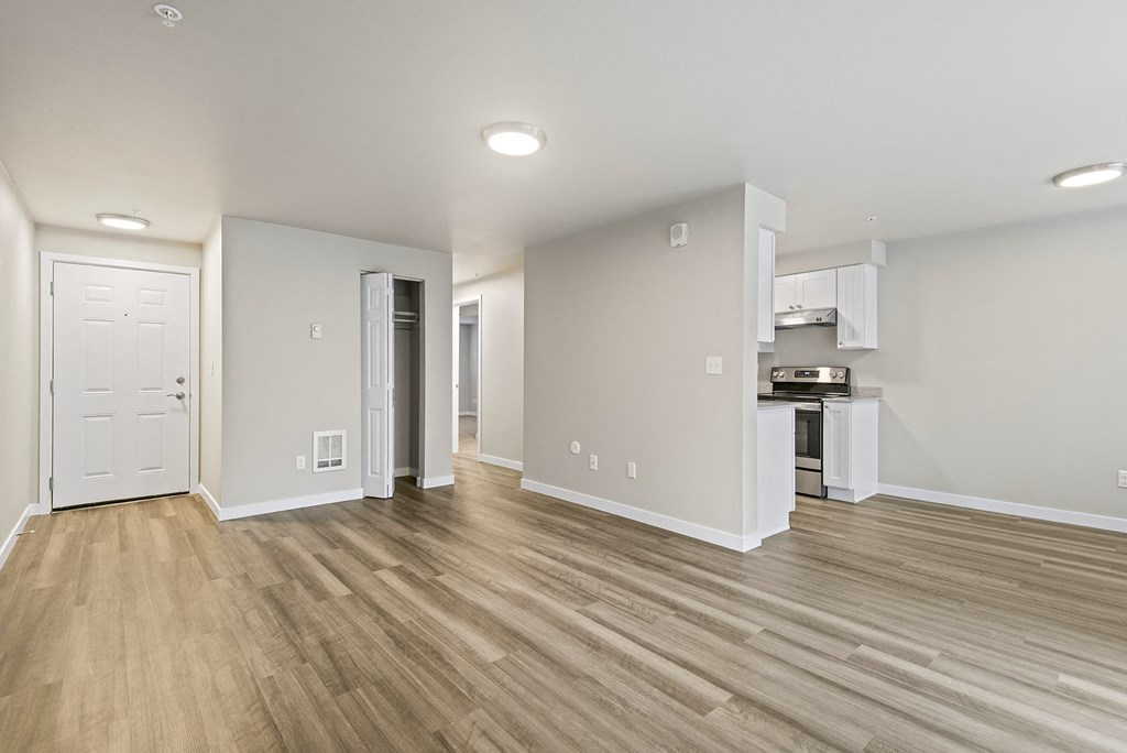 a renovated living room with wood flooring and a kitchen