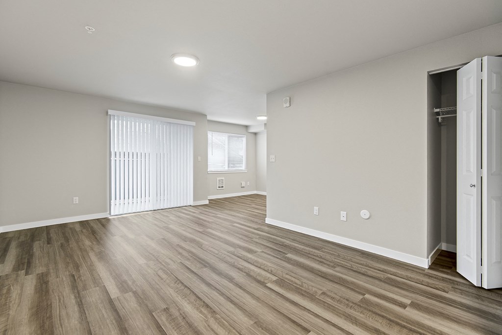 an empty living room with hardwood flooring and a closet