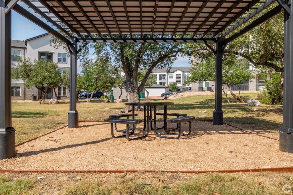 A picnic table is set up under a canopy in a park.