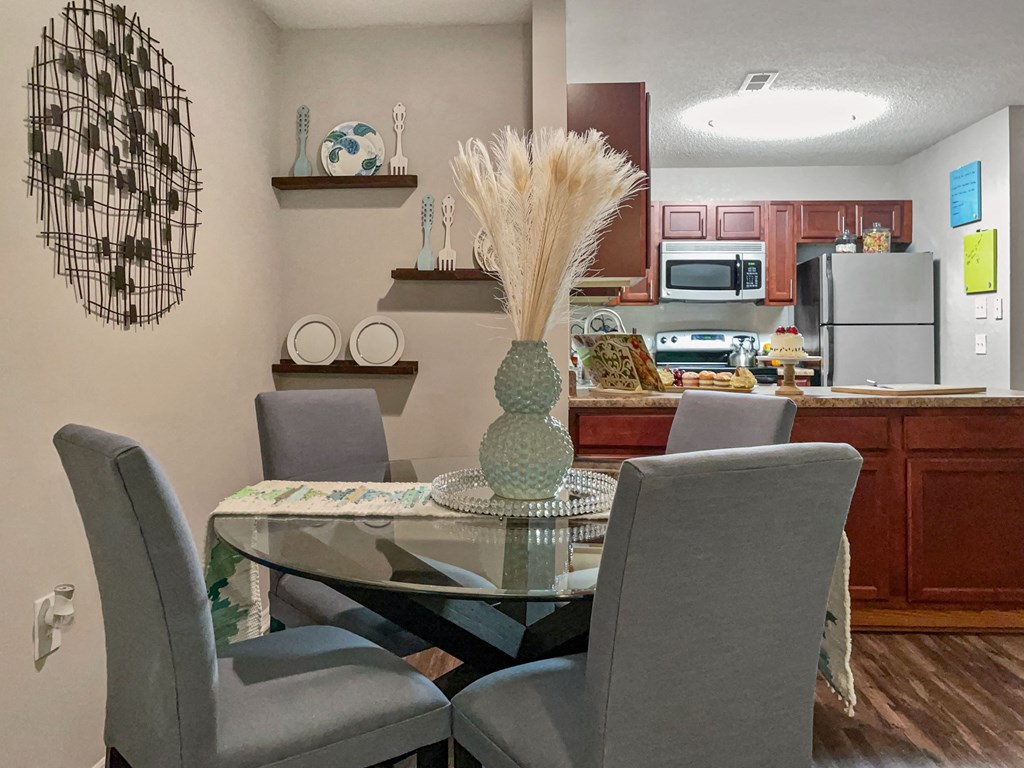 a dining room with a glass table and chairs and a kitchen