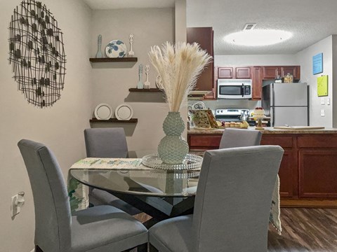 A dining room with a glass table and grey chairs.