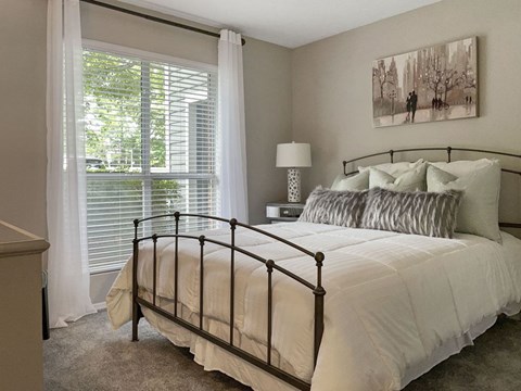 A bedroom with a large bed and a painting on the wall.