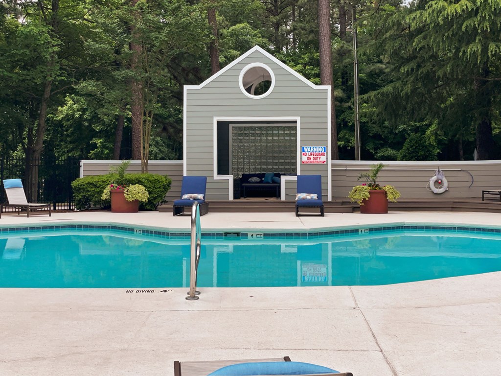 a swimming pool with a pool house in the background