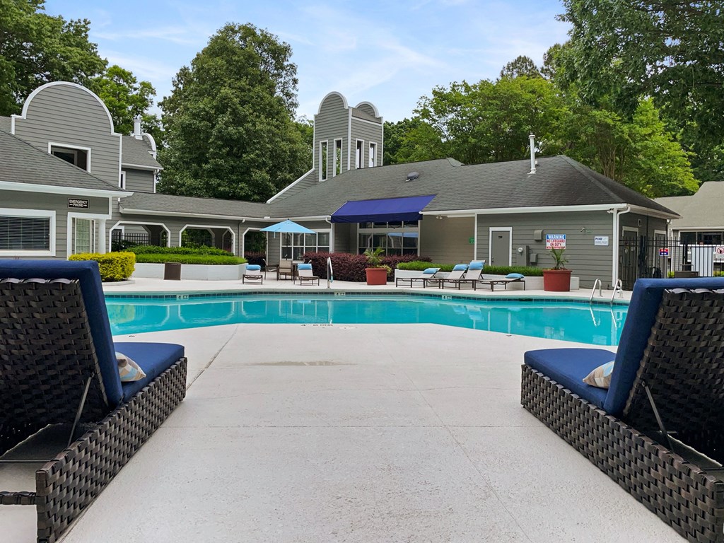 a swimming pool with lounge chairs and a house in the background