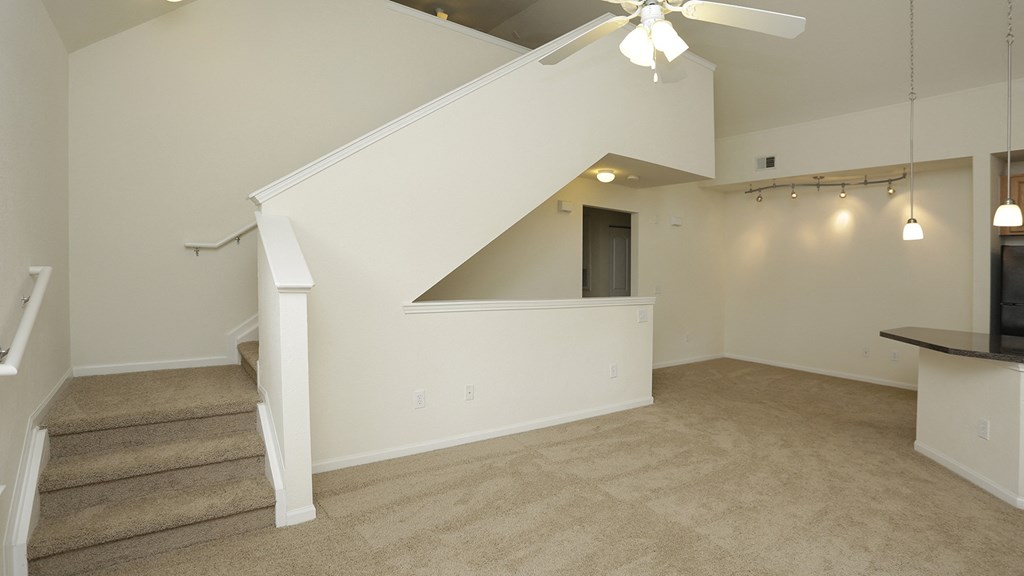 A room with a staircase and a ceiling fan.