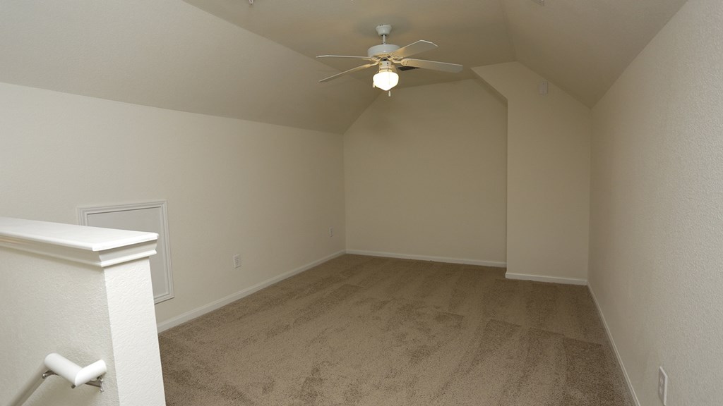 A room with a ceiling fan and carpeted floor.